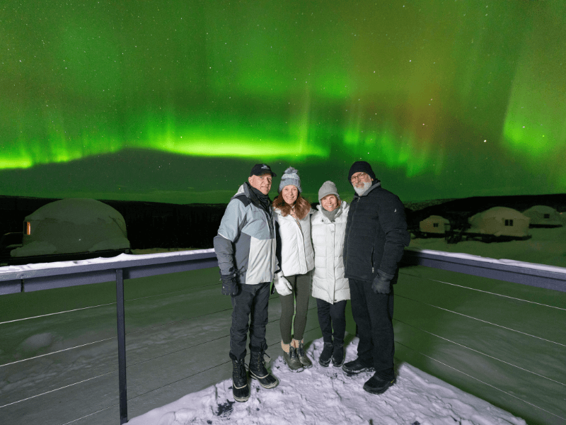 People on a deck with the Northern Lights behind them